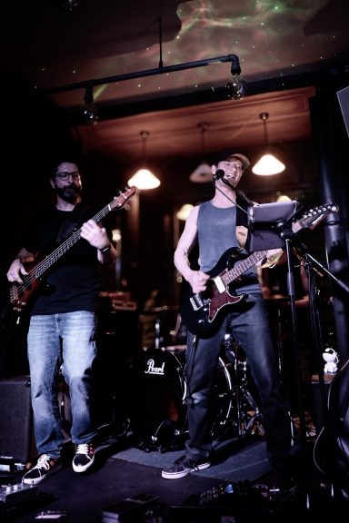 Live Musik im Sir Capulus Füssen - Konzert in der Bar im Allgäu Live-Band im Sir Capulus in Füssen: Zwei Musiker mit E-Gitarre und Bass spielen auf der Bühne, Konzertatmosphäre in der Bar im Allgäu.